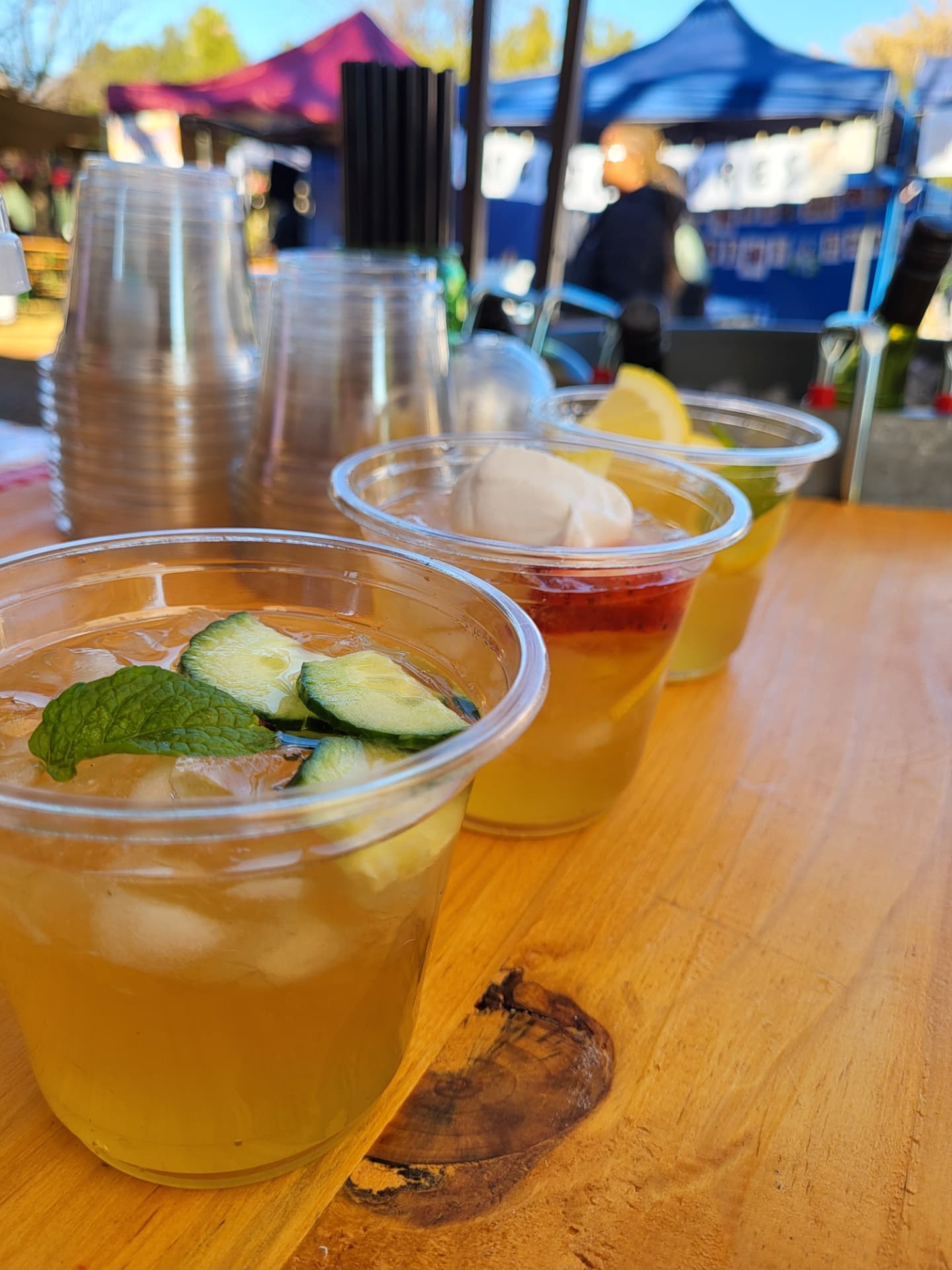 Colourful kombucha cups garnished with cucumber and mint at an outdoor market